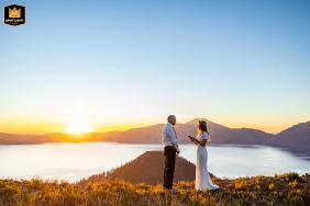 A bride and groom's elopement on the rim of Crater Lake, Oregon, as the sun rises over the water.